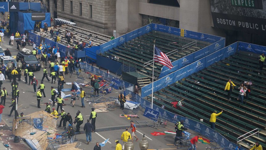 Emergency workers attend the scene of the explosion on the Boston marathon route after spectators left the event.