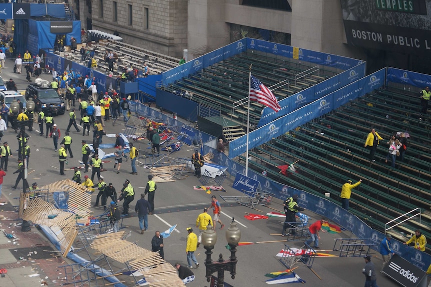 Emergency workers attend the scene of the explosion on the Boston marathon route after spectators left the event.
