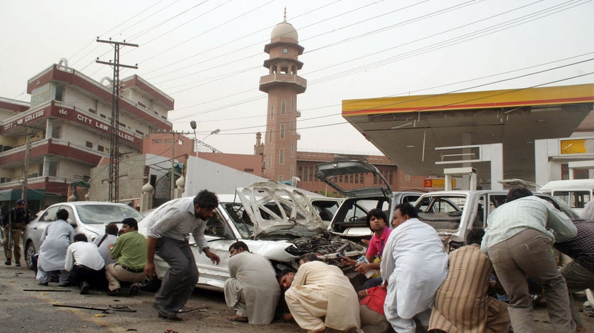 Pakistani media take cover outside one of two mosques stormed by gunmen in Pakistan