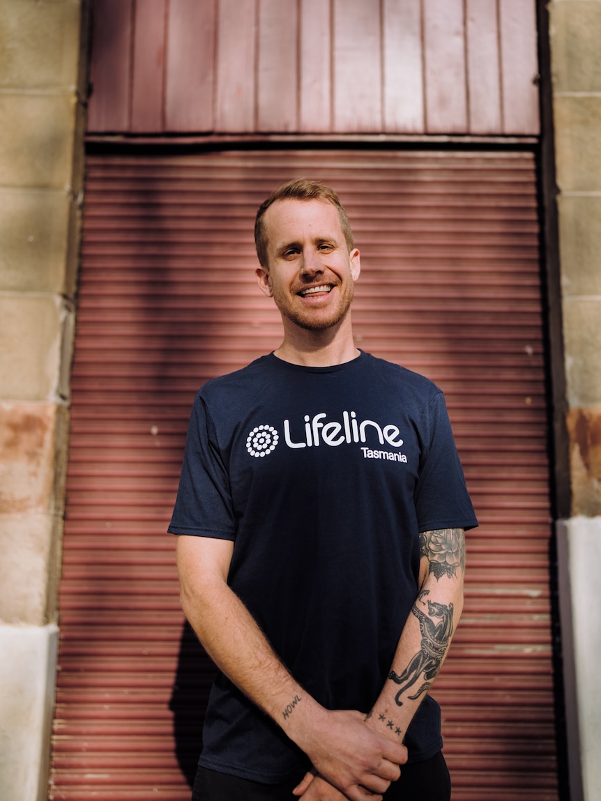 a man in a blue tshirt that says LifeLine is standing up smiling at the camera