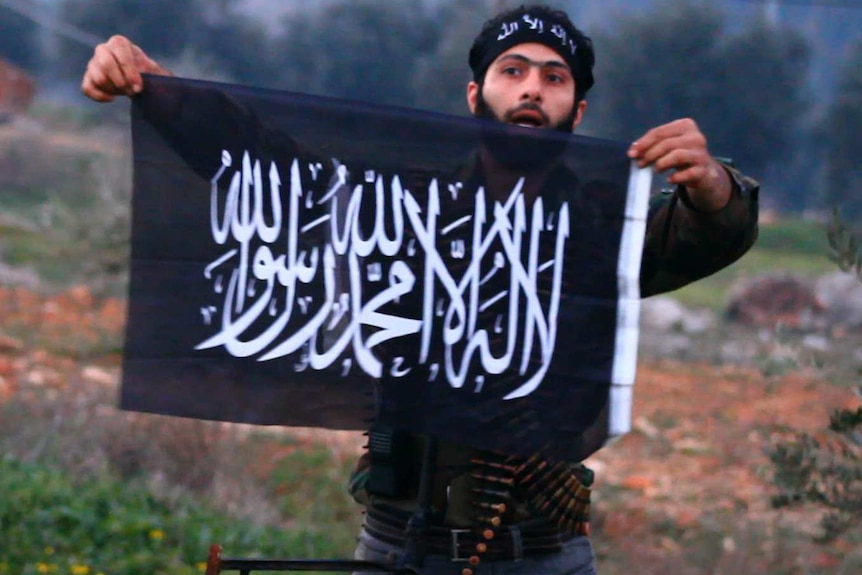 A rebel fighter holds an Islamic flag in Idlib province