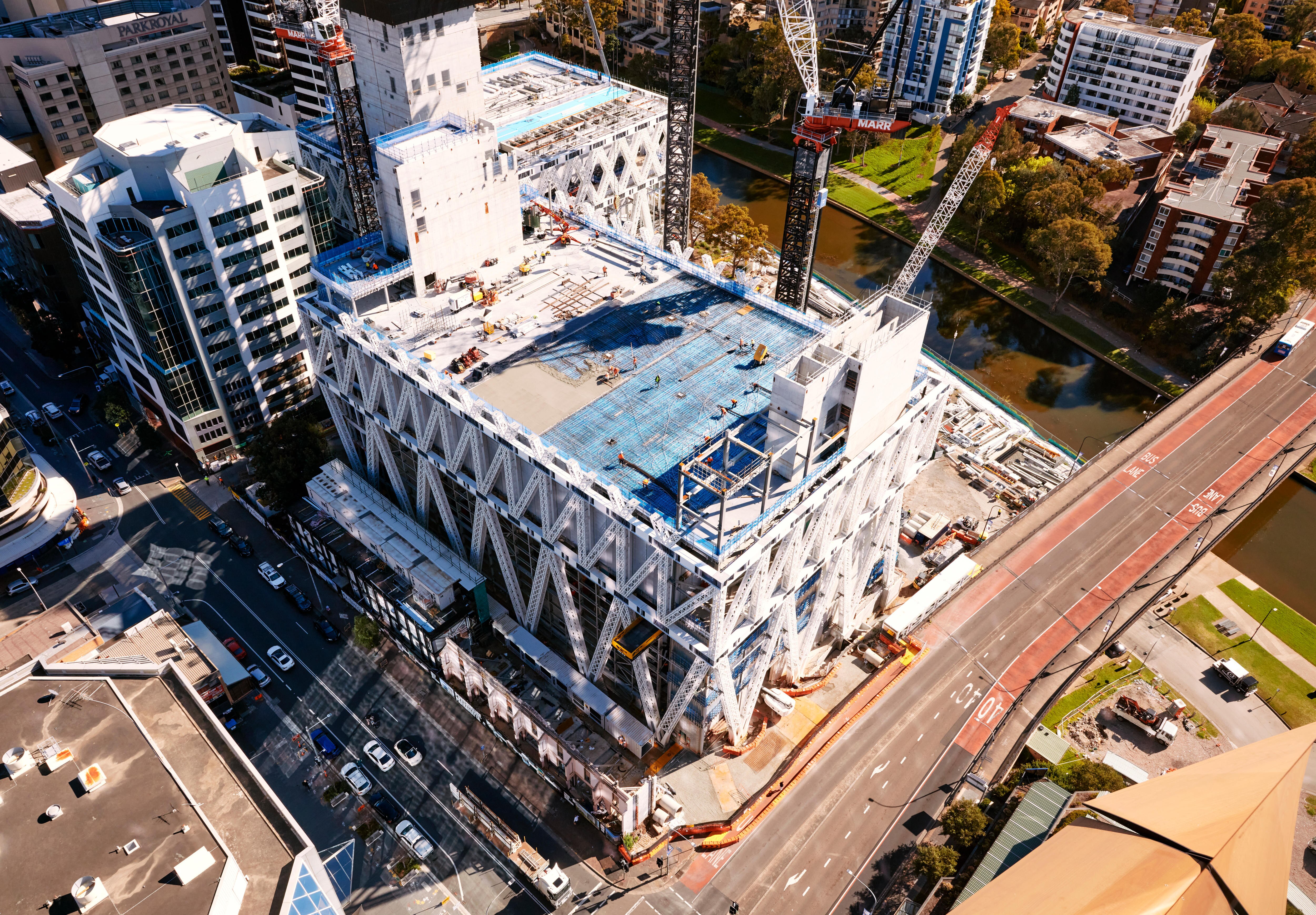A wide, tall white building next to other buildings and roads.