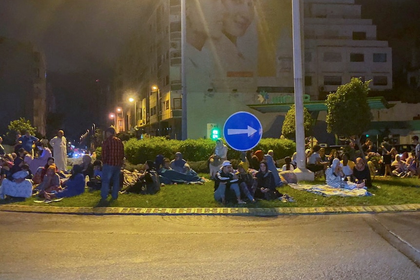 People sitting on a road island in night time. 