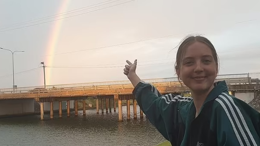 A young woman pointing at a rainbow