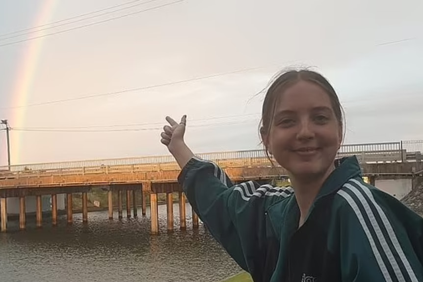 A young woman pointing at a rainbow