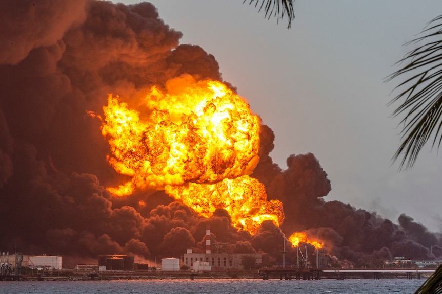 A massive fireball towers over an industrial building. 