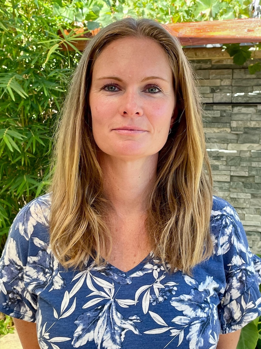 Woman in a blue and white printed top standing in a garden.