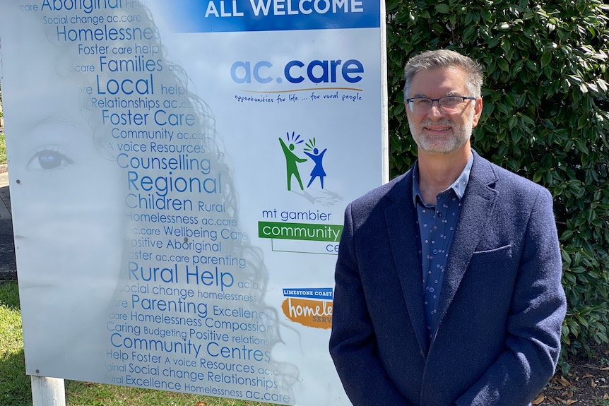 A man stands in front of an ac.care sign.