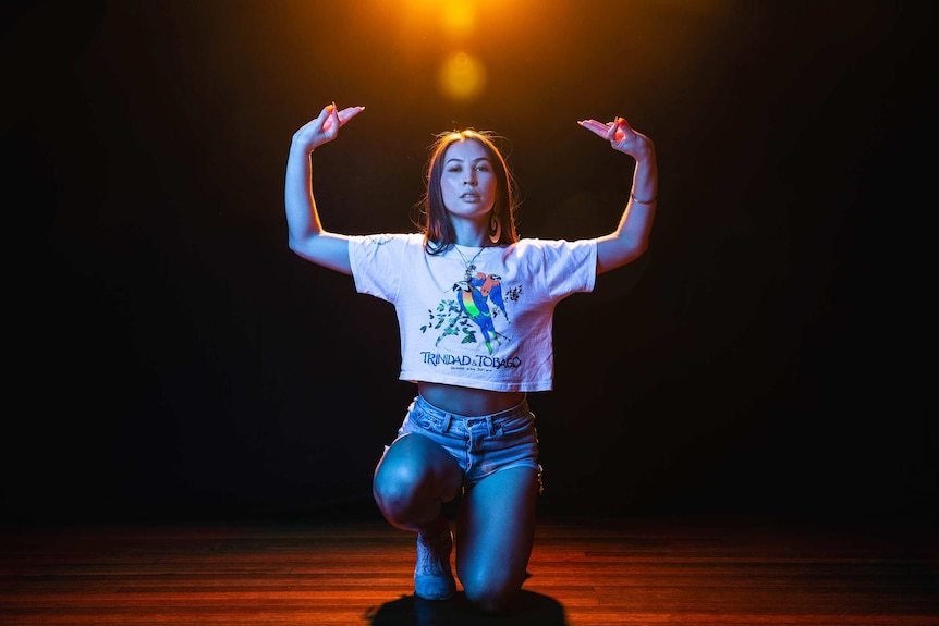 A dramatic wide colour portrait of Bhenji Ra posing in front of dark background.