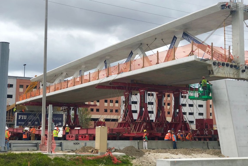 Workers construct the pedestrian bridge at Florida International University