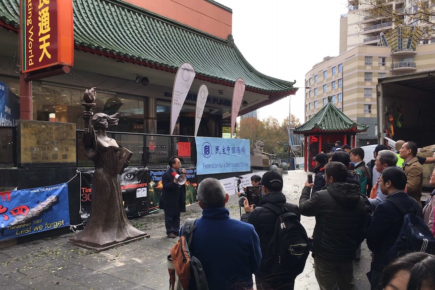 Chin Jin speaks on a megaphone to a crowd.