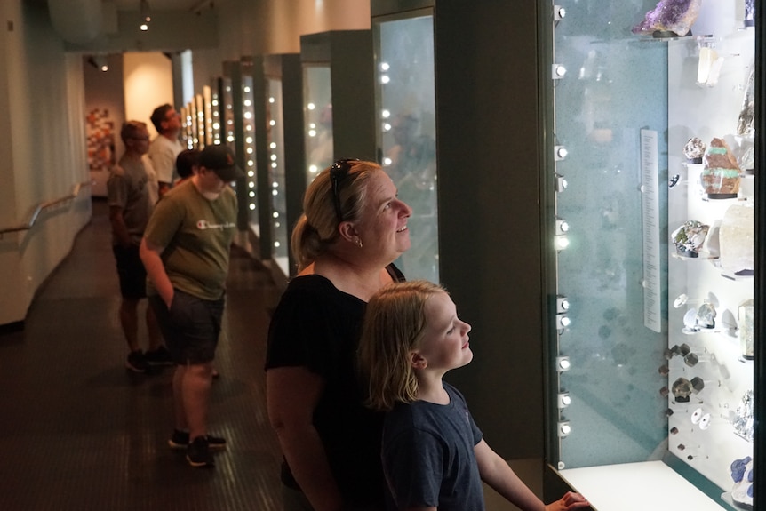 People stare at an exhibit and smile.