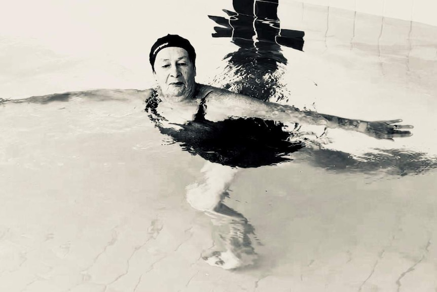 A woman  stands on one leg in a ballerina pose in the water