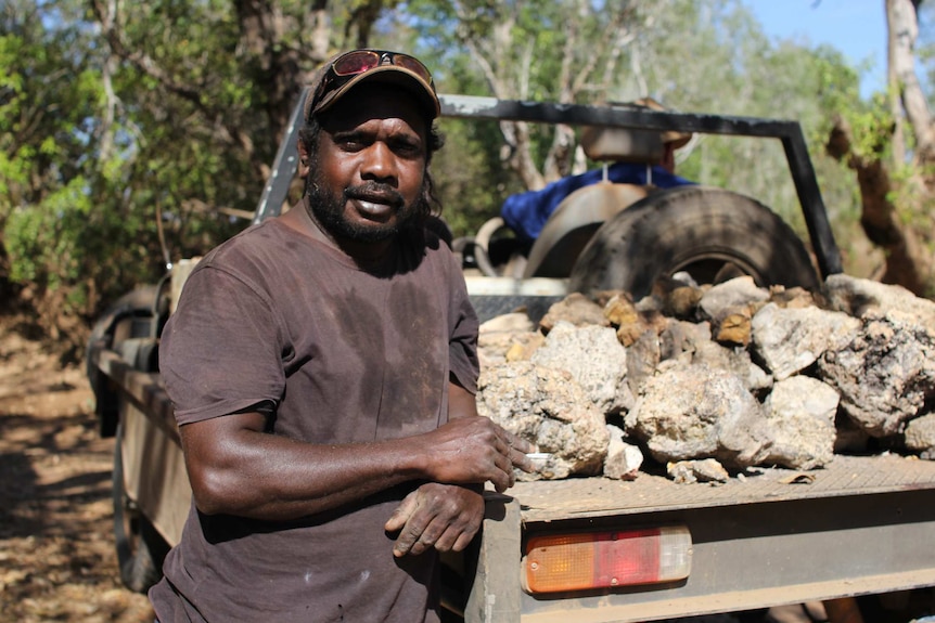 Wayne Runyu leans on the edge of a ute tray, smoking a cigarette.