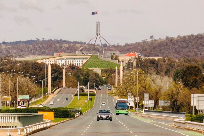Cars driving over bridge with Parliament House in the background. 