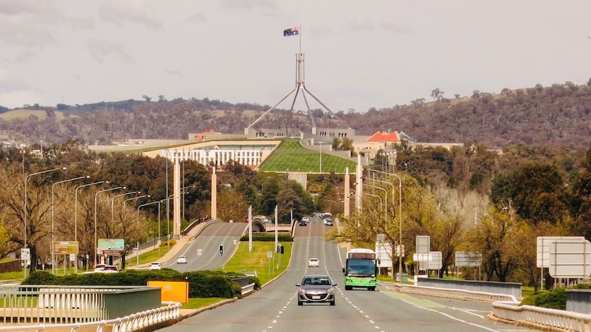 Cars driving over bridge with Parliament House in the background. 