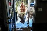 Maura Walbourne sits in the front of a canoe looking in at her flooded home