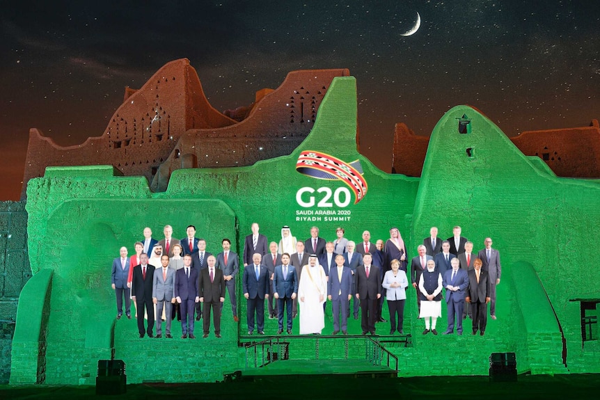 A picture of members of the G20 is projected onto a green lite wall.