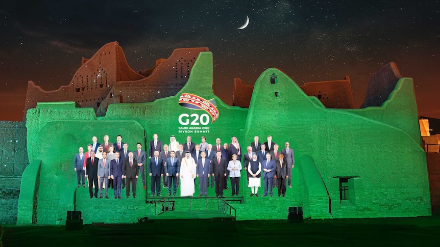 A picture of members of the G20 is projected onto a green lite wall.