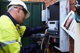 Worker installs power equipment on a house exterior