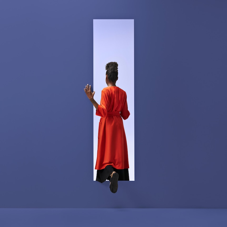 Back of woman wearing an orange dress stepping through rectangle opening