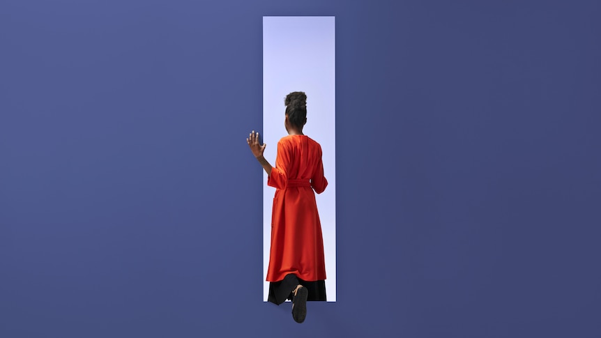 Back of woman wearing an orange dress stepping through rectangle opening