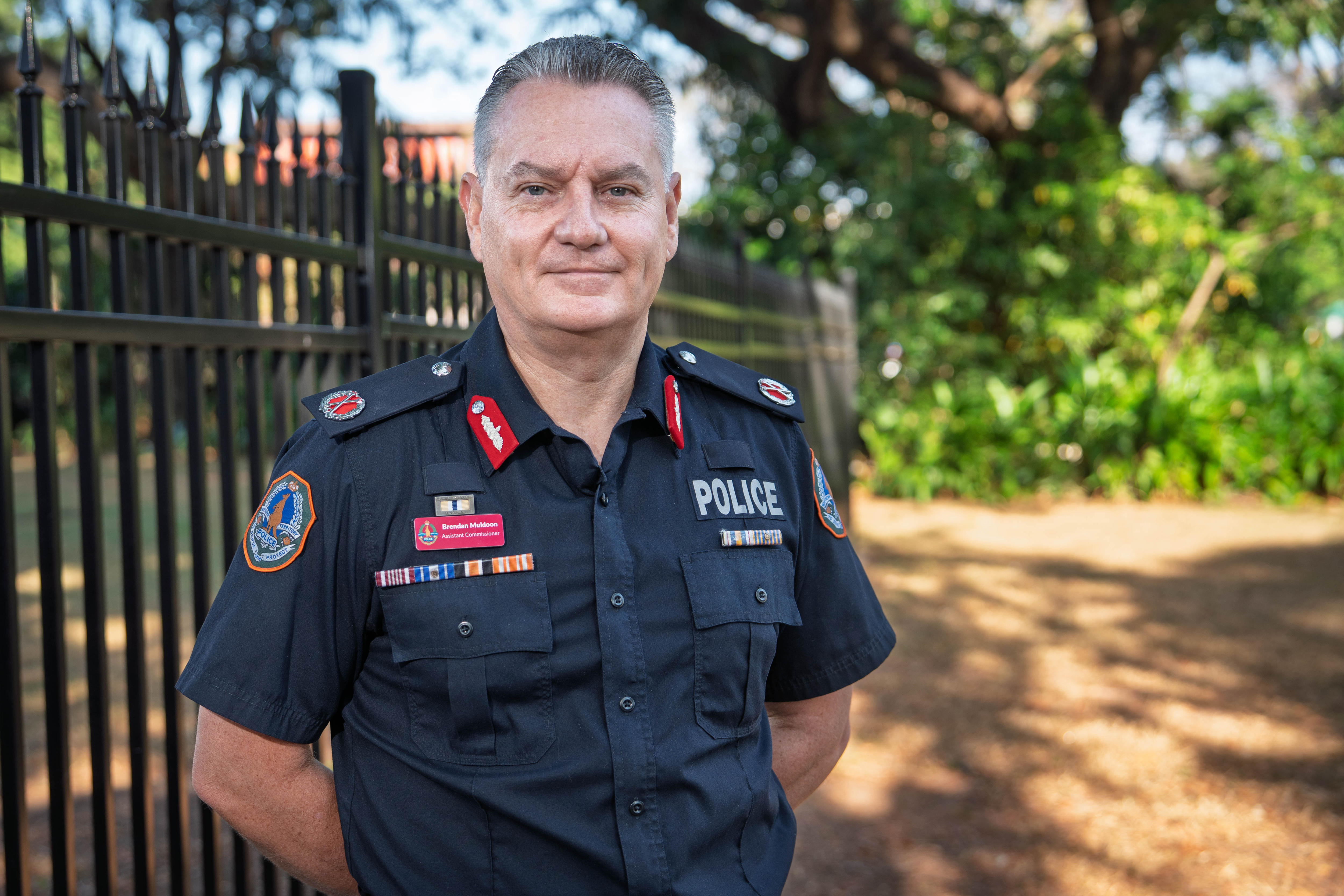 A police officer in uniform looks at the camera.