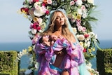 Beyonce cradles the second and third in line to the throne in front of a fabulous backdrop of flowers. She is slaying.