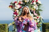 Beyonce cradles her twins in front of a backdrop of flowers.