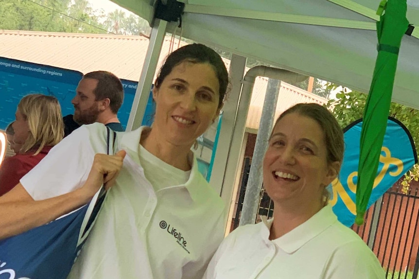 two ladies smiling standing next to each other wearing white lifeline tops