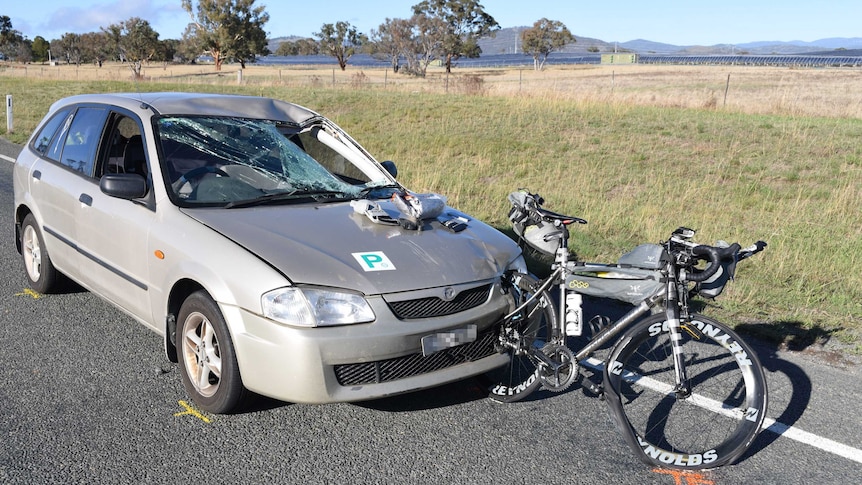 A police photograph shows a bicycle impaled in a car's front bumper, the windscreen smashed.