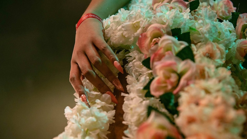 Closeup image of vogue performer's flower costume and long, pink nails at Sissy Ball 2019.