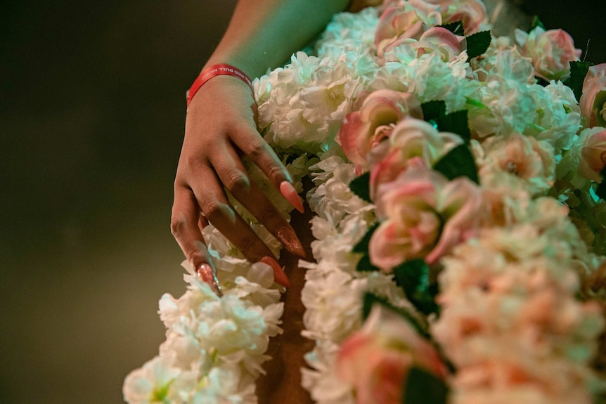 Closeup image of vogue performer's flower costume and long, pink nails at Sissy Ball 2019.