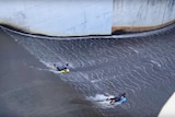 Two people surfing down a dam.