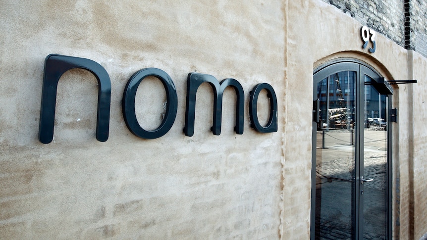 A brick wall with a sign which reads "noma"