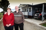 Pam and John Bond standing out front of their demountable house in a caravan park in Bendigo.