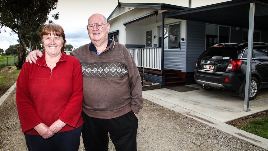Pam and John Bond standing out front of their demountable house in a caravan park in Bendigo.