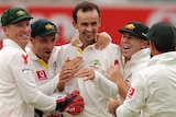 Nathan Lyon is hugged by team-mates after taking his first Test wicket.