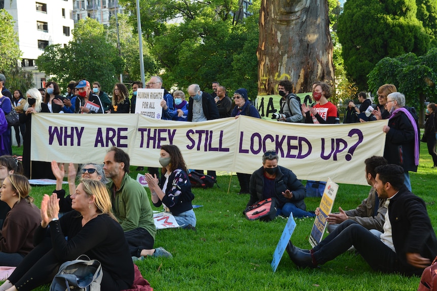 Proesters hold a sign reading: 'Why are they still locked up?'