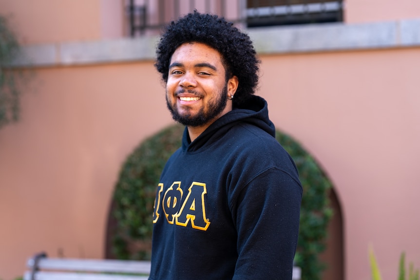 African American college student wearing a navy hoodie.