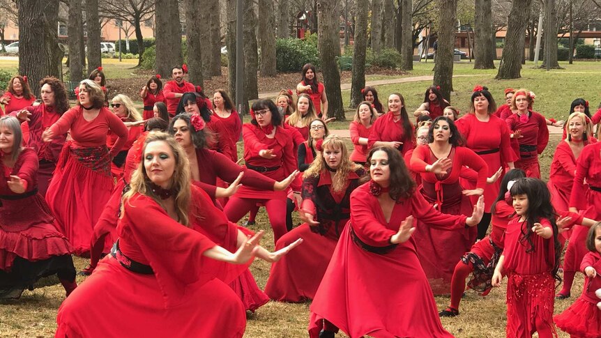 Sea of people dressed in red dresses and skirts perform interpretive dance
