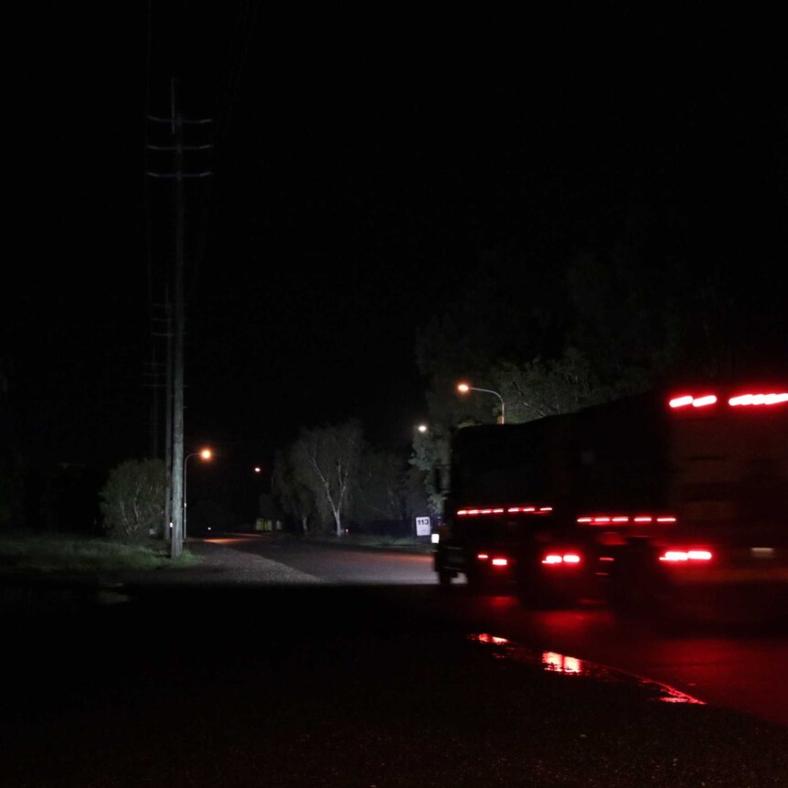 A truck passes on a dark road at night.