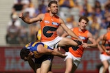 Stephen Coniglio kicks the ball as Luke Shuey attempts a smother