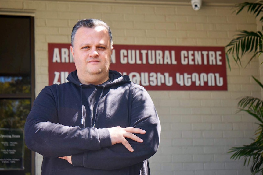 Haig Kayserian standing with his arms folded in front of the Armenian cultural centre.