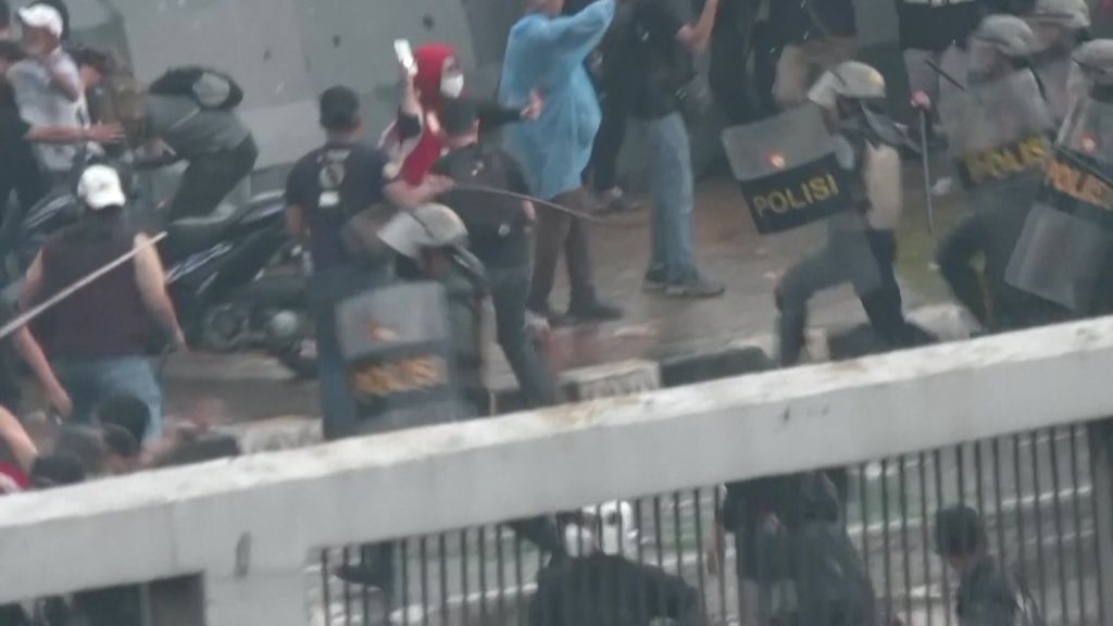 Police in Indonesia run towards protesters with batons. 