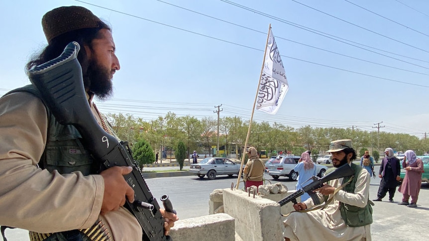 Taliban fighters stand guard at an entrance gate outside the Interior Ministry in Kabul