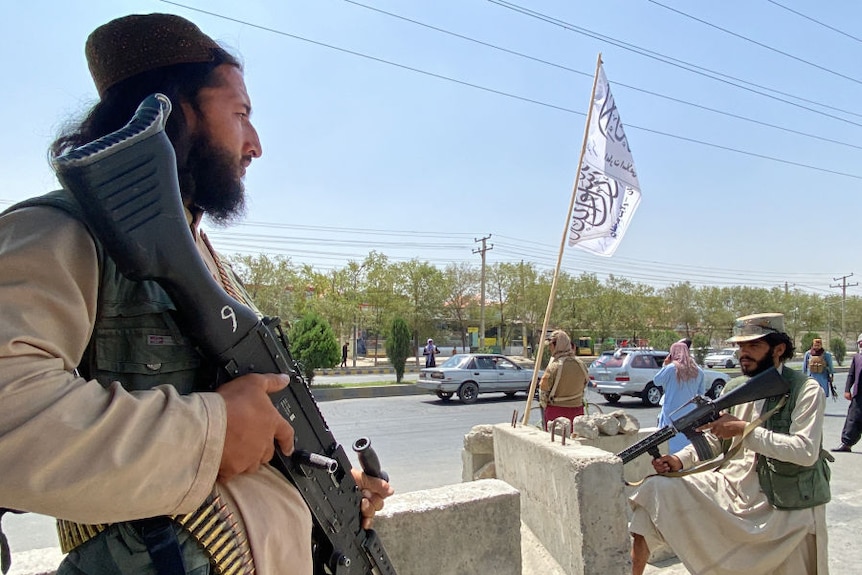 Taliban fighters stand guard at an entrance gate outside the Interior Ministry in Kabul