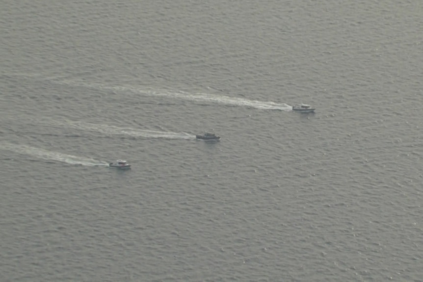 Three boats seen from the air in low light.