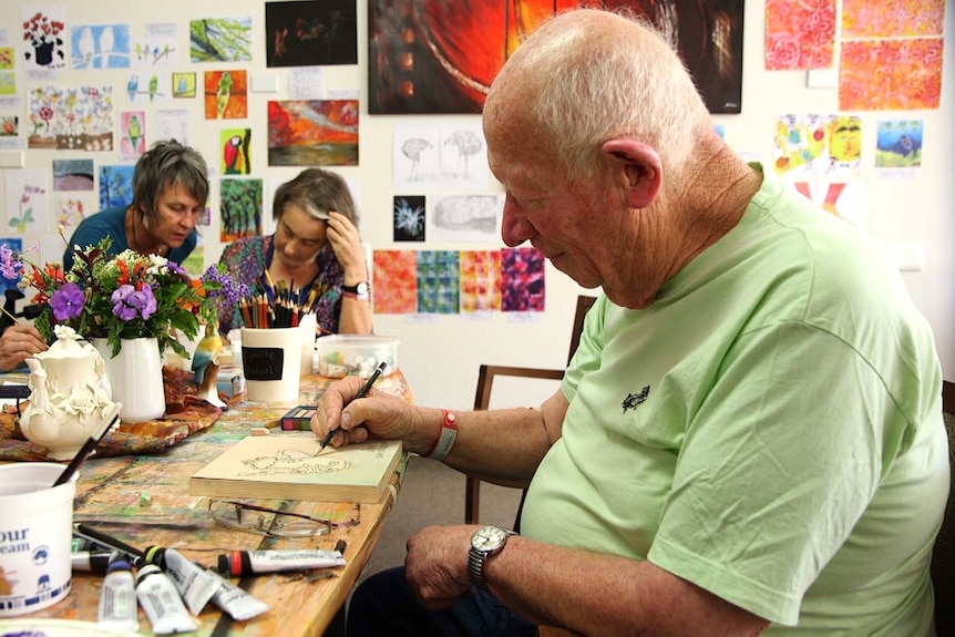 Patient Sam sketching an imitation of a white tea pot in the centre of the table.