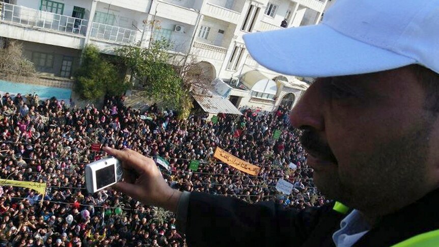 An Arab League observer takes photos for anti-government protesters on the streets in Adlb in Syria.